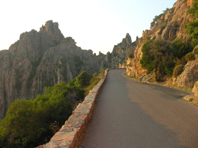 A winding road through mountain scenery at sunset in Corsica