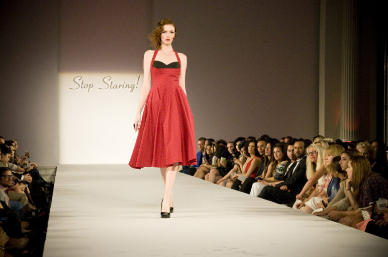 Woman in red swing dress walking down runway