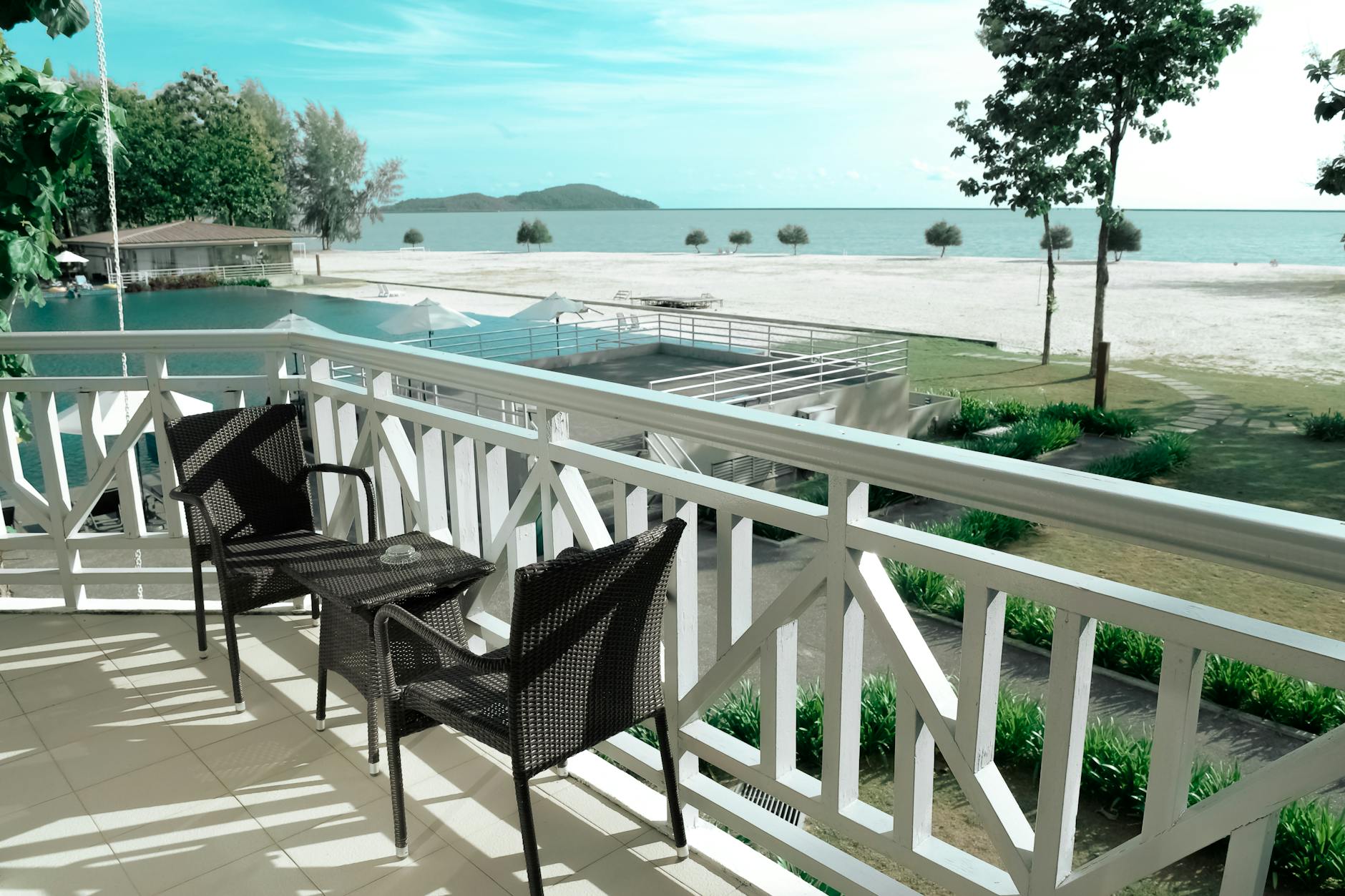 black wicker bistro set on white balcony near ocean