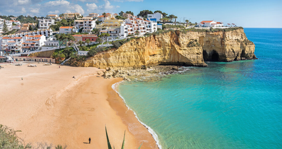 Whitewashed houses on a cliff above a golden beach in the Algarve