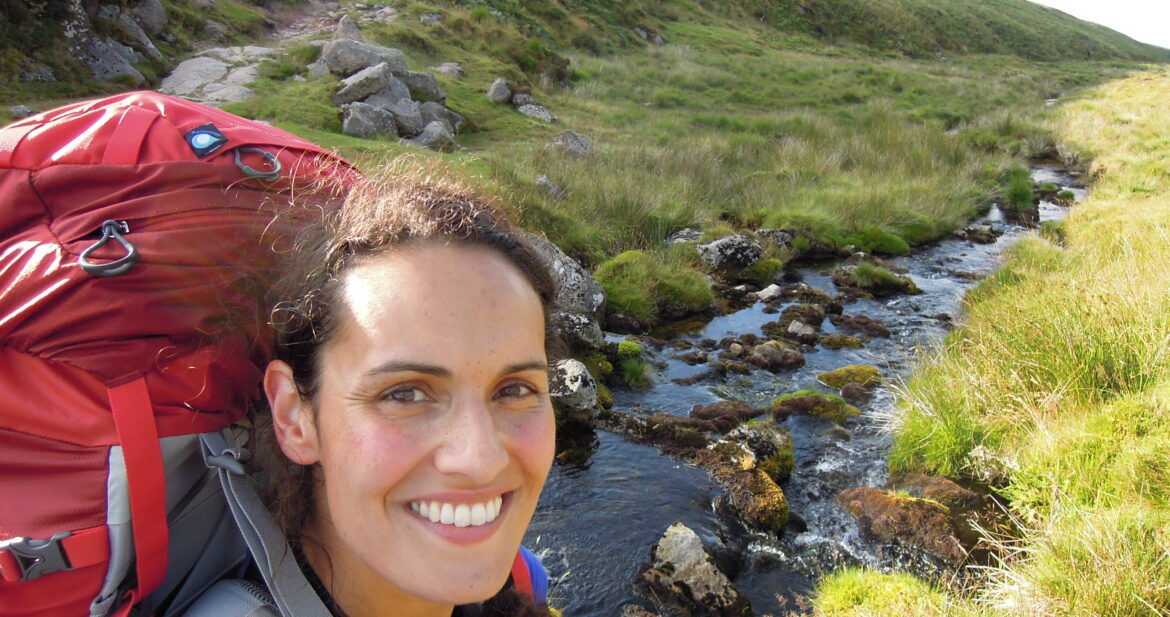 Women wearing a backpack while hiking in the countryside