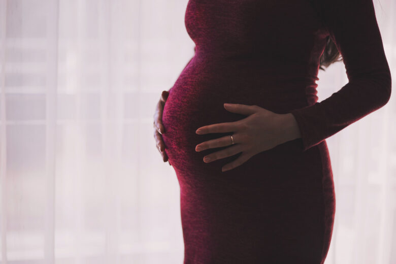 Lady in red dress holding her baby bump