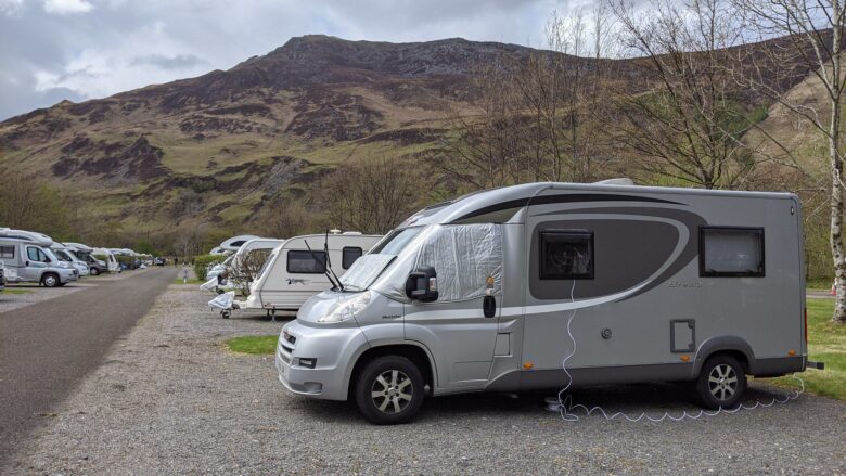 A row of caravans and motorhomes parked in a campsite