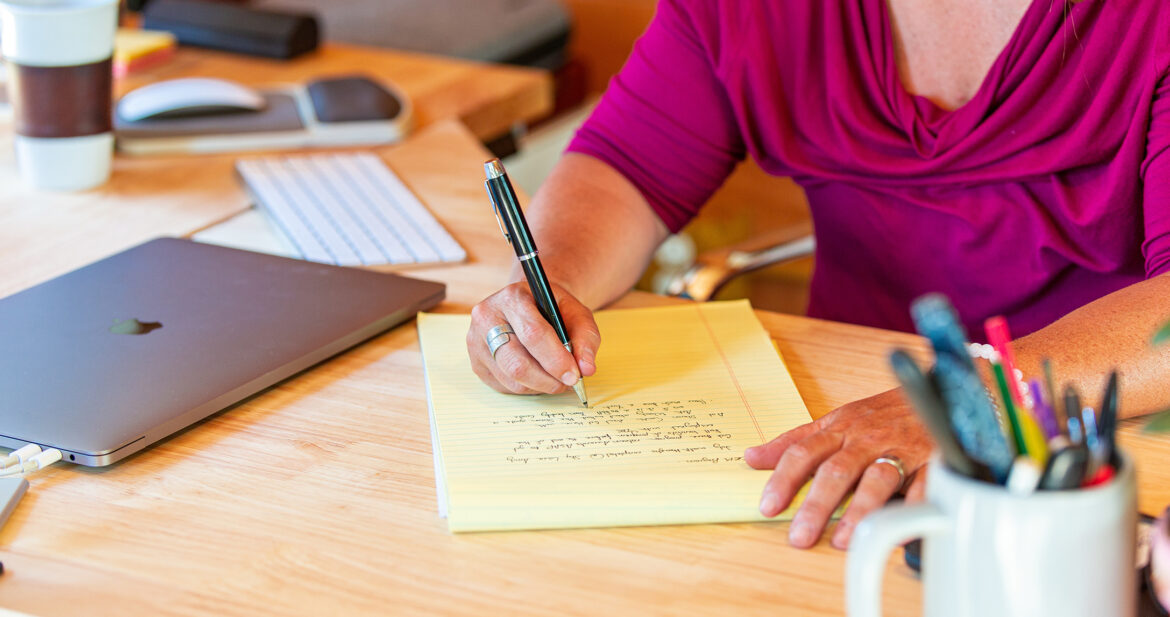 Women writing on a notepad on a remote working desk