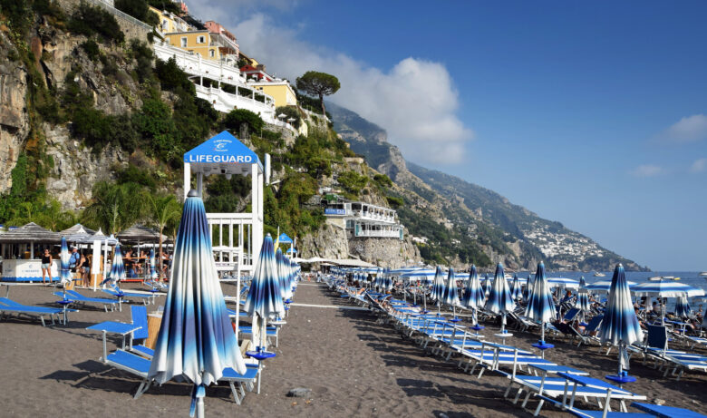 Umbrellas and sun loungers lined up on a beach in the Amalfi Coast